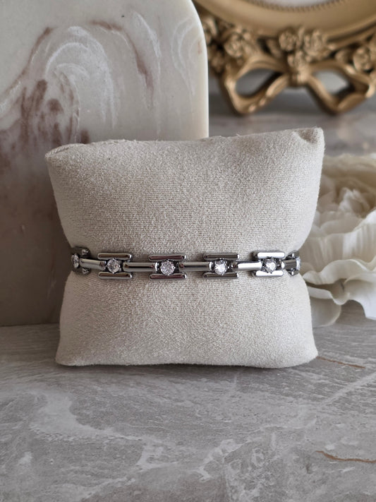 Jayda Bracelet in silver, featuring polished geometric chain links accented with sparkling clear stones, styled on a model’s wrist with neutral beige knitwear.