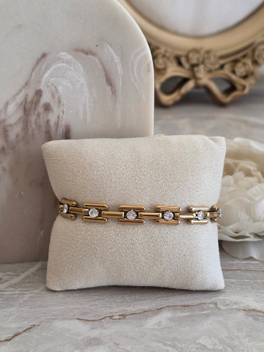 Gold Jayda Bracelet featuring a modern link design with sparkling round crystal accents, displayed on a beige jewellery cushion.