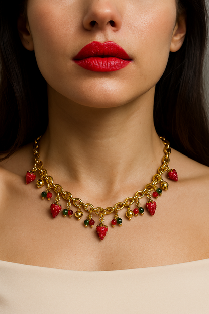 Gold chain necklace with cute strawberry charms, green and red beads, and small gold ball accents displayed on a mannequin bust.