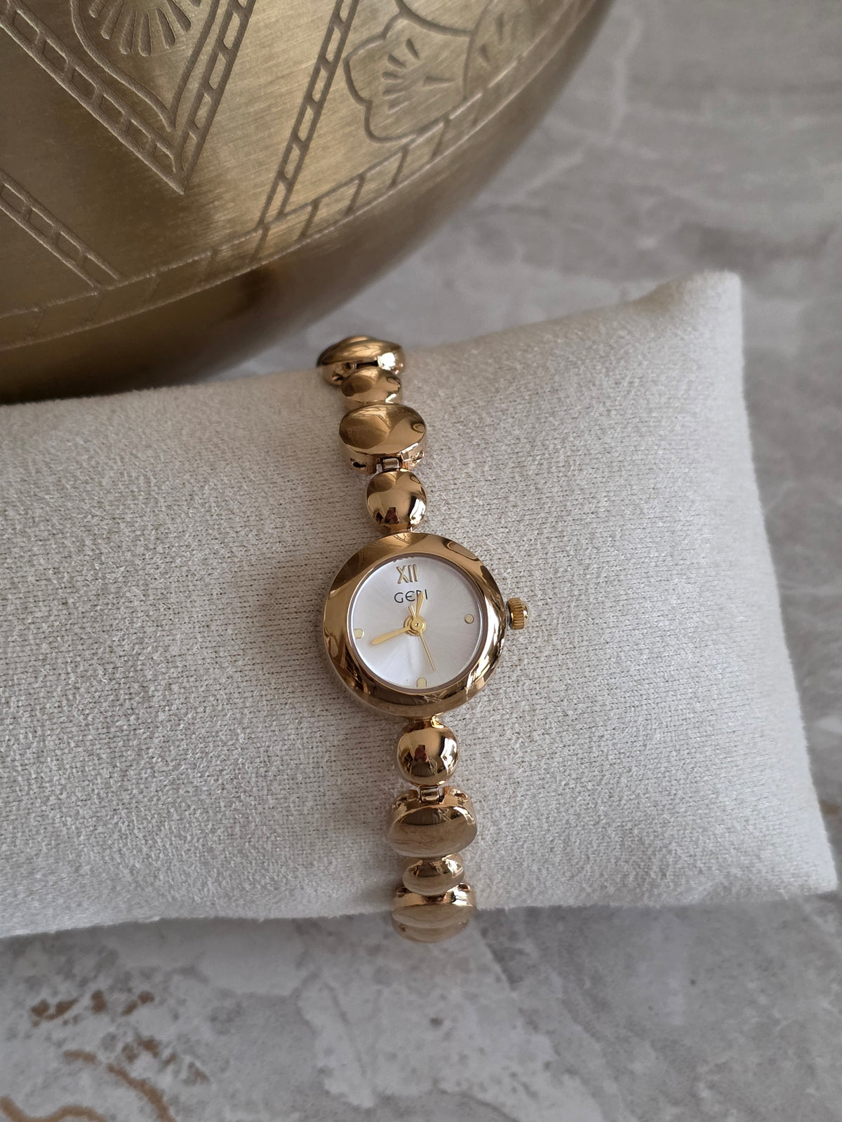 Gold Nera Watch featuring a petite round silver-toned dial and a jewellery-inspired bracelet band with smooth sculpted gold-tone links.
