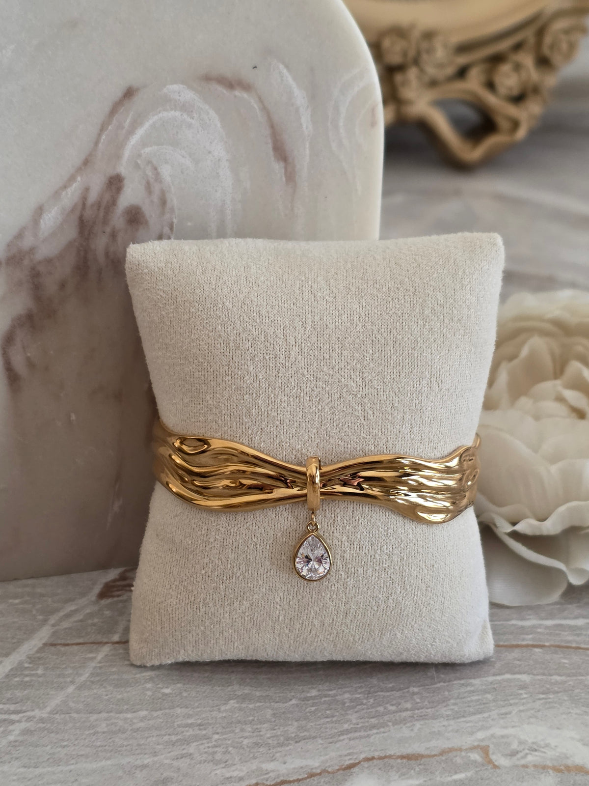 Zina gold cuff bangle with sculptural wave design and sparkling teardrop crystal charm.