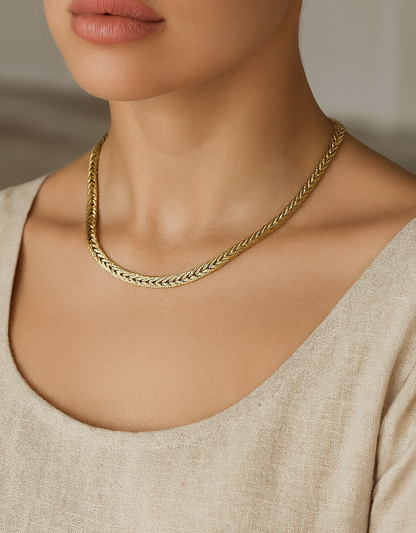 Gold herringbone stainless steel necklace displayed on a mannequin bust with a smooth, flat chain design.