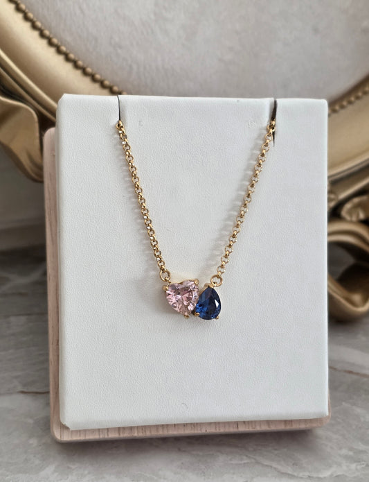 Lilay Necklace with pink heart and blue teardrop stones on a delicate gold chain.