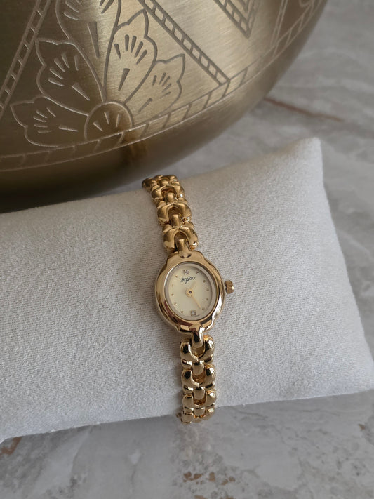 Gold stainless steel women’s watch featuring a petite oval face, champagne dial and elegant jewellery-inspired bracelet band.