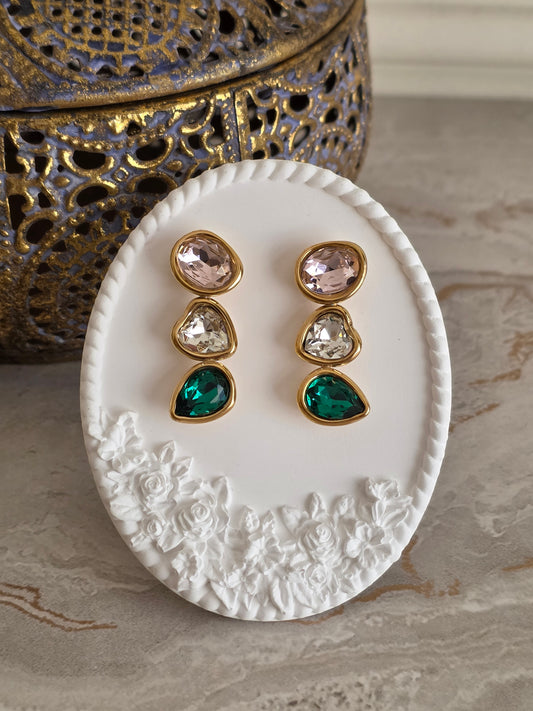 Aresa Earrings featuring three faceted stones in blush pink, champagne and emerald green, set in gold-tone frames with an elegant cascading drop design.