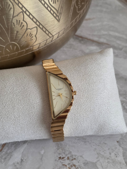 Melodi gold stainless steel watch featuring a unique asymmetrical face, champagne dial and slim gold-tone bracelet band.