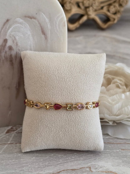 Zara Bangle in gold featuring multi-coloured pink, berry and champagne stones in assorted shapes and cuts.