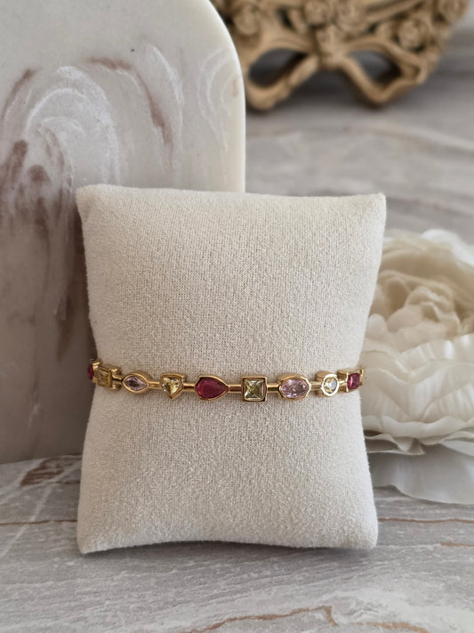 Zara Bangle in gold featuring multi-coloured pink, berry and champagne stones in assorted shapes and cuts.