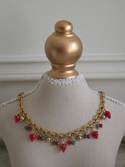 Gold chain necklace with cute strawberry charms, green and red beads, and small gold ball accents displayed on a mannequin bust.
