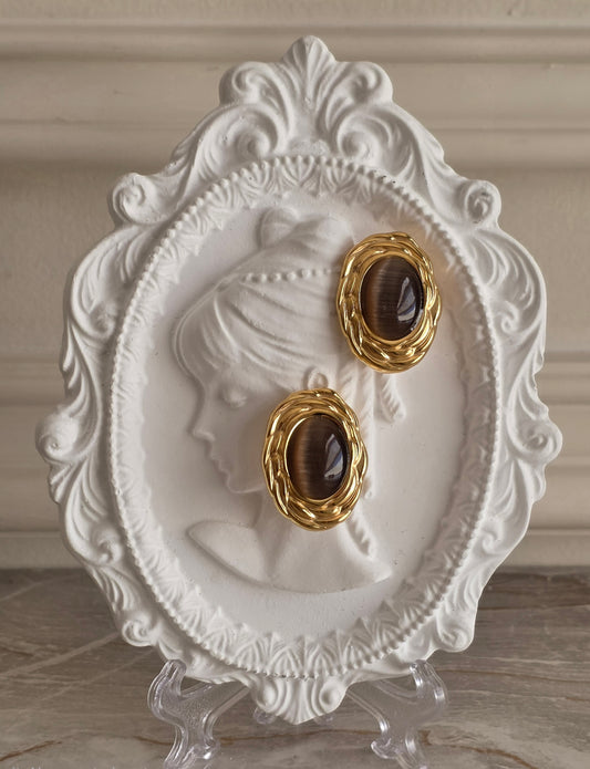 Mayda Brown Earrings featuring an oval brown cat's-eye glass insert framed by a textured gold-tone stainless steel setting.