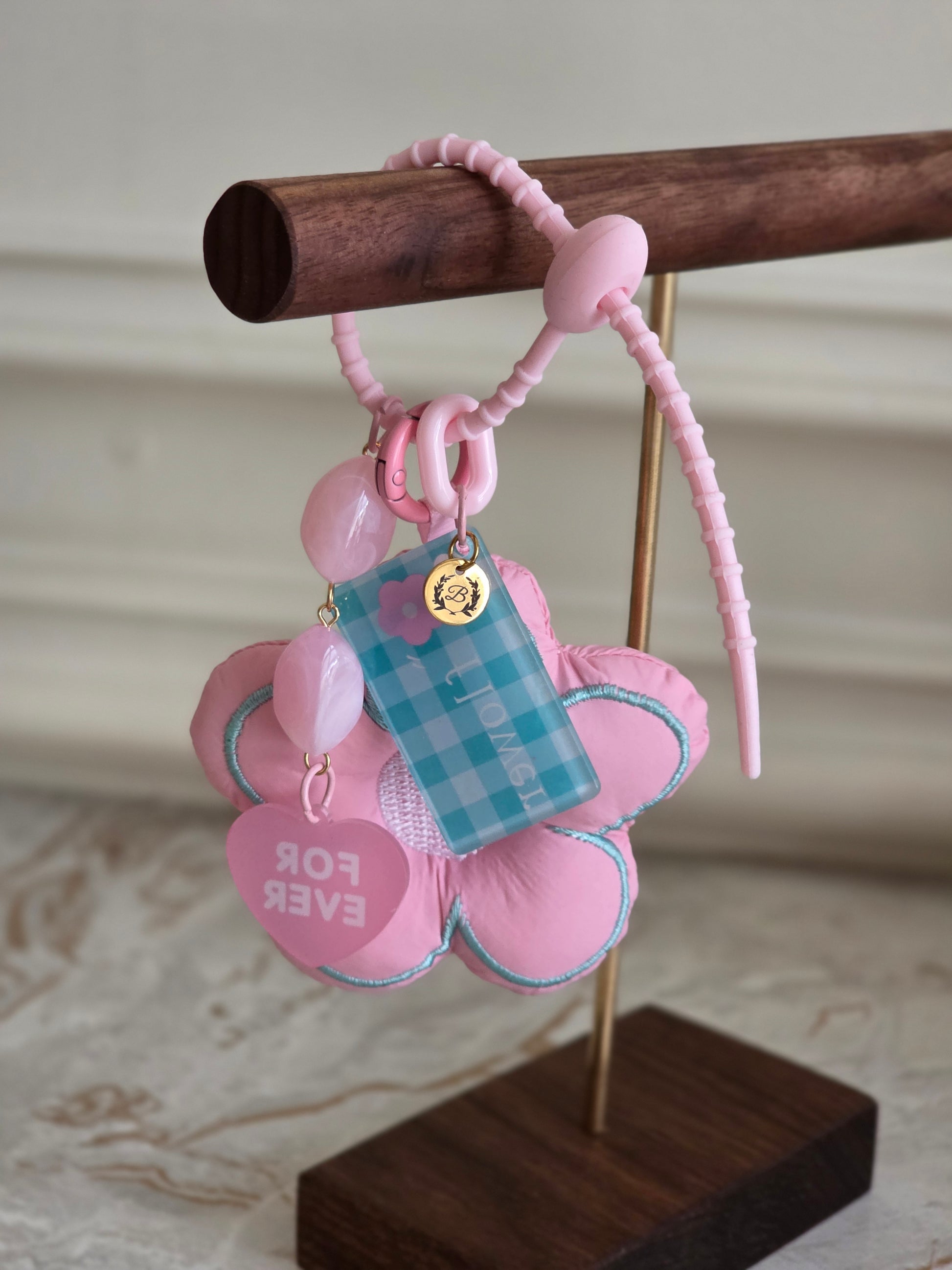 Cute pink flower keychain with heart-shaped charm that says “Forever,” pastel beads, and a blue gingham tag