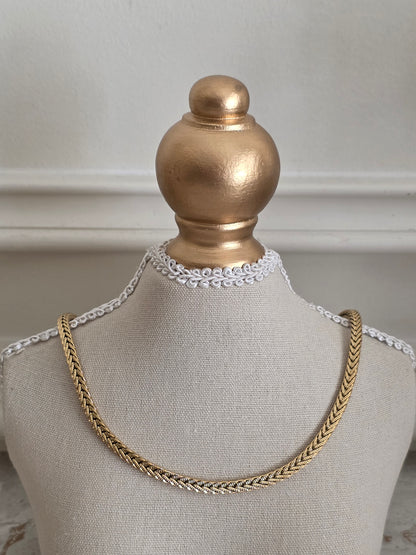 Gold herringbone stainless steel necklace displayed on a mannequin bust with a smooth, flat chain design.