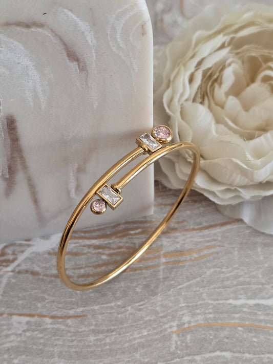 Gold Alaya Bangle with a double-band design featuring soft pink round stones and clear rectangular stones.